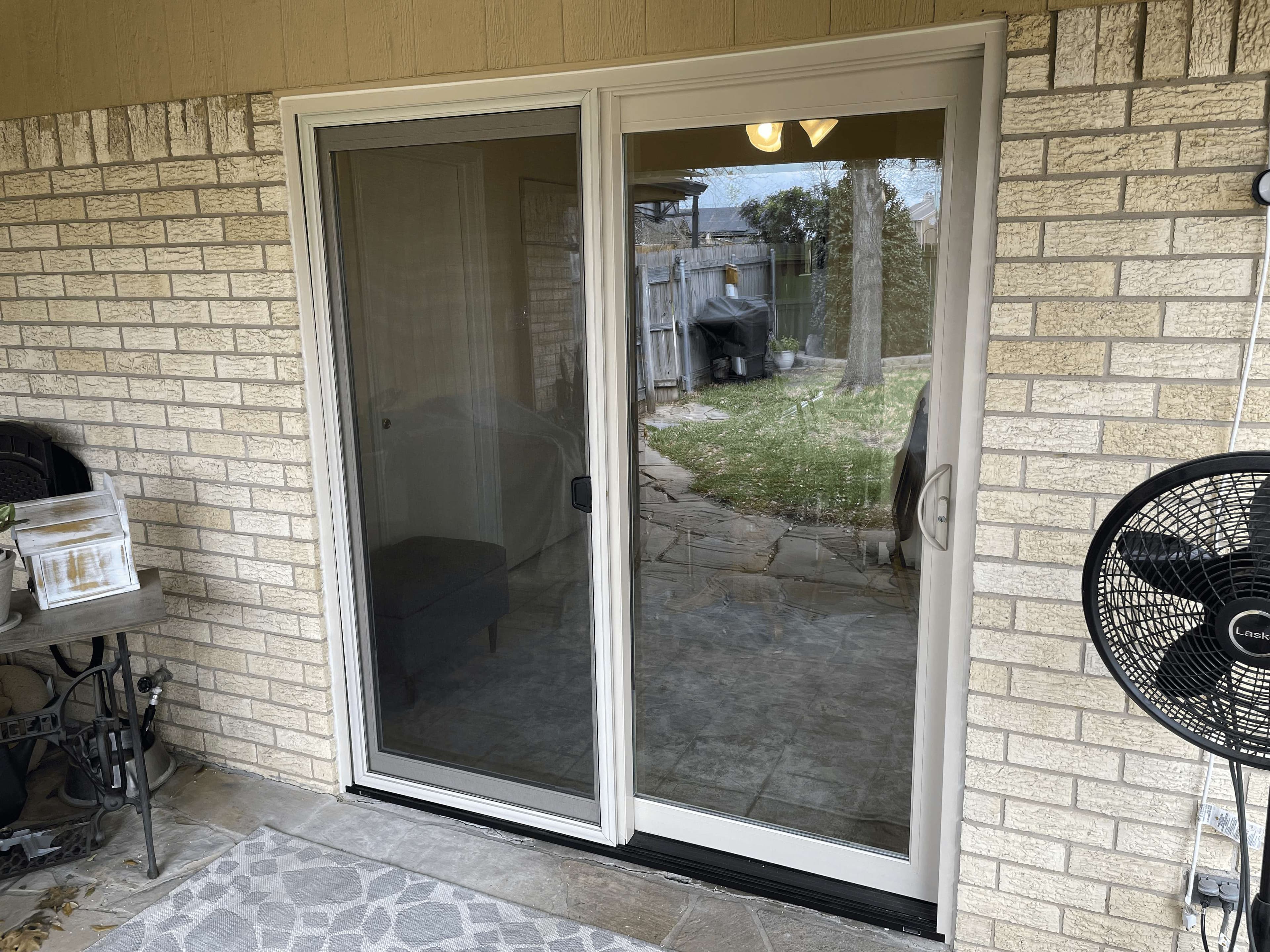 White framed sliding patio door on tan cream brick covered patio